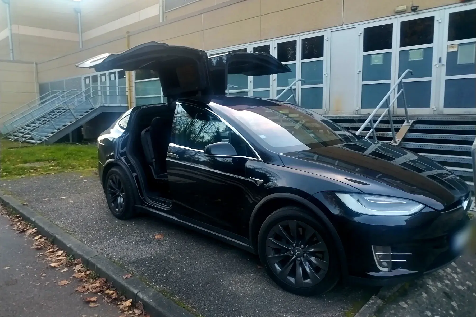 La Tesla Model X noire de PrestigeGo vue de trois quarts avant, les deux portes arrière papillon levées