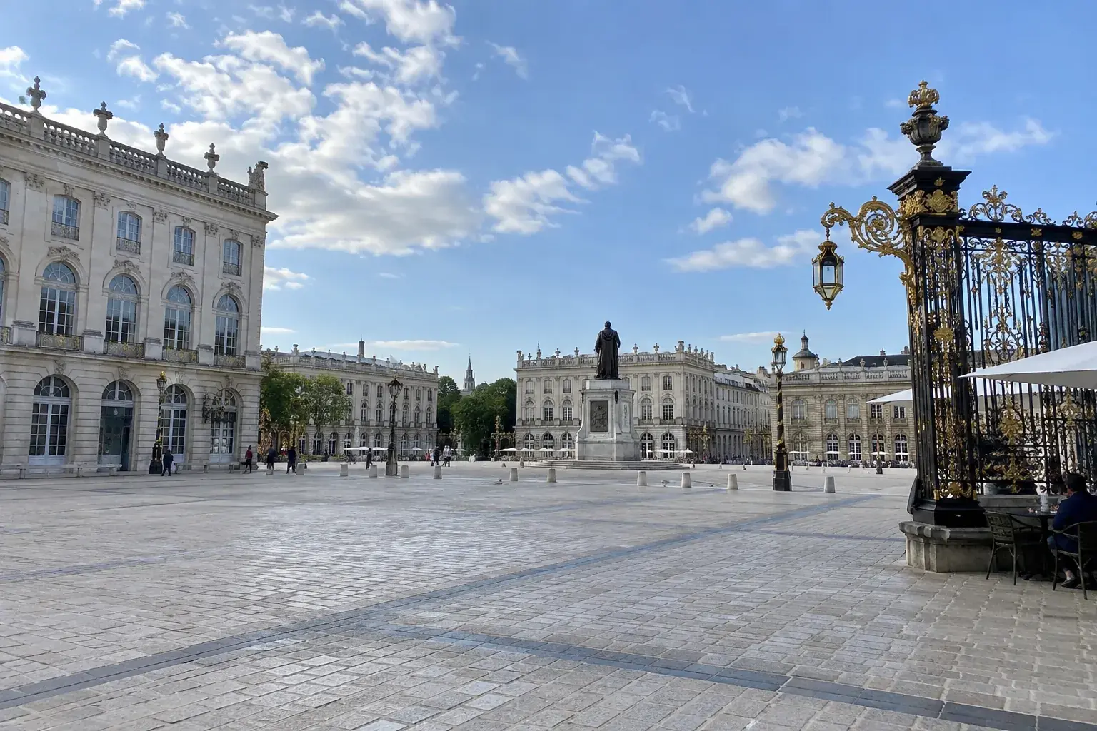 La place Stanislas à Nancy : grand pavage clair, façades du XVIIIᵉ siècle et grilles en fer forgé rehaussées d’or, sous un ciel bleu